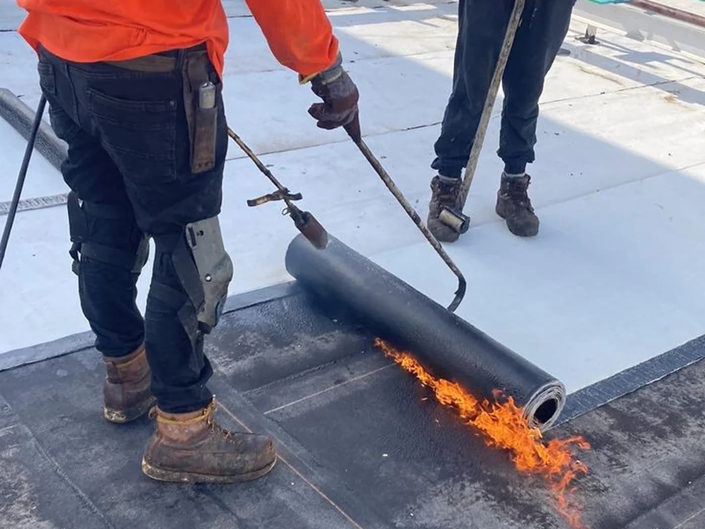 Équipe posant une membrane bitume au chalumeau